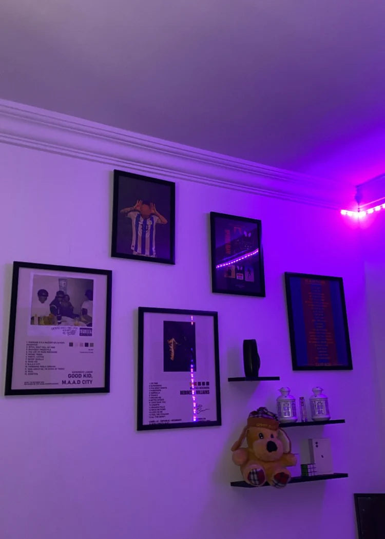 A gallery wall of black Spark frames in a room lit purple