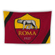 A flag features the emblem of the AS Roma football club. The emblem includes a depiction of the mythological she-wolf suckling the twins Romulus and Remus, set against a yellow background on the upper half and a red background on the lower half. The word "ROMA" and the year "1927" are written below the image. The flag has black diagonal stripes on both the top left and bottom right corners.