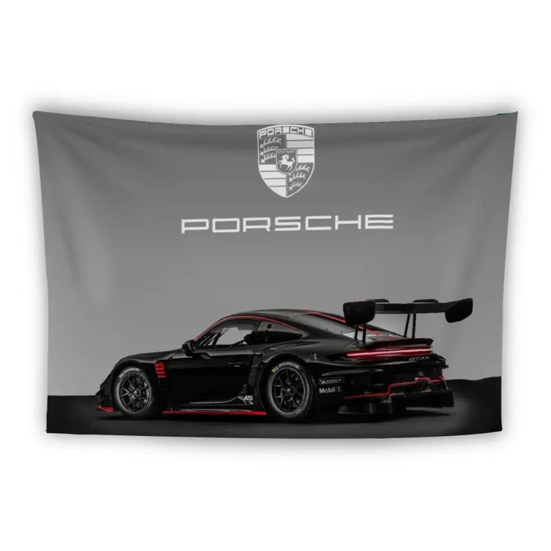 A black Porsche race car with red accents and a prominent rear wing is featured against a gray background. Above the car, the Porsche logo and text are displayed. The image is stylized as a banner or poster.