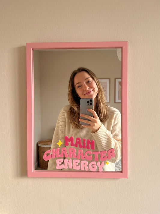 Pink wood-framed wall mirror with Main Character Energy in pink bubble lettering and sparkle icons