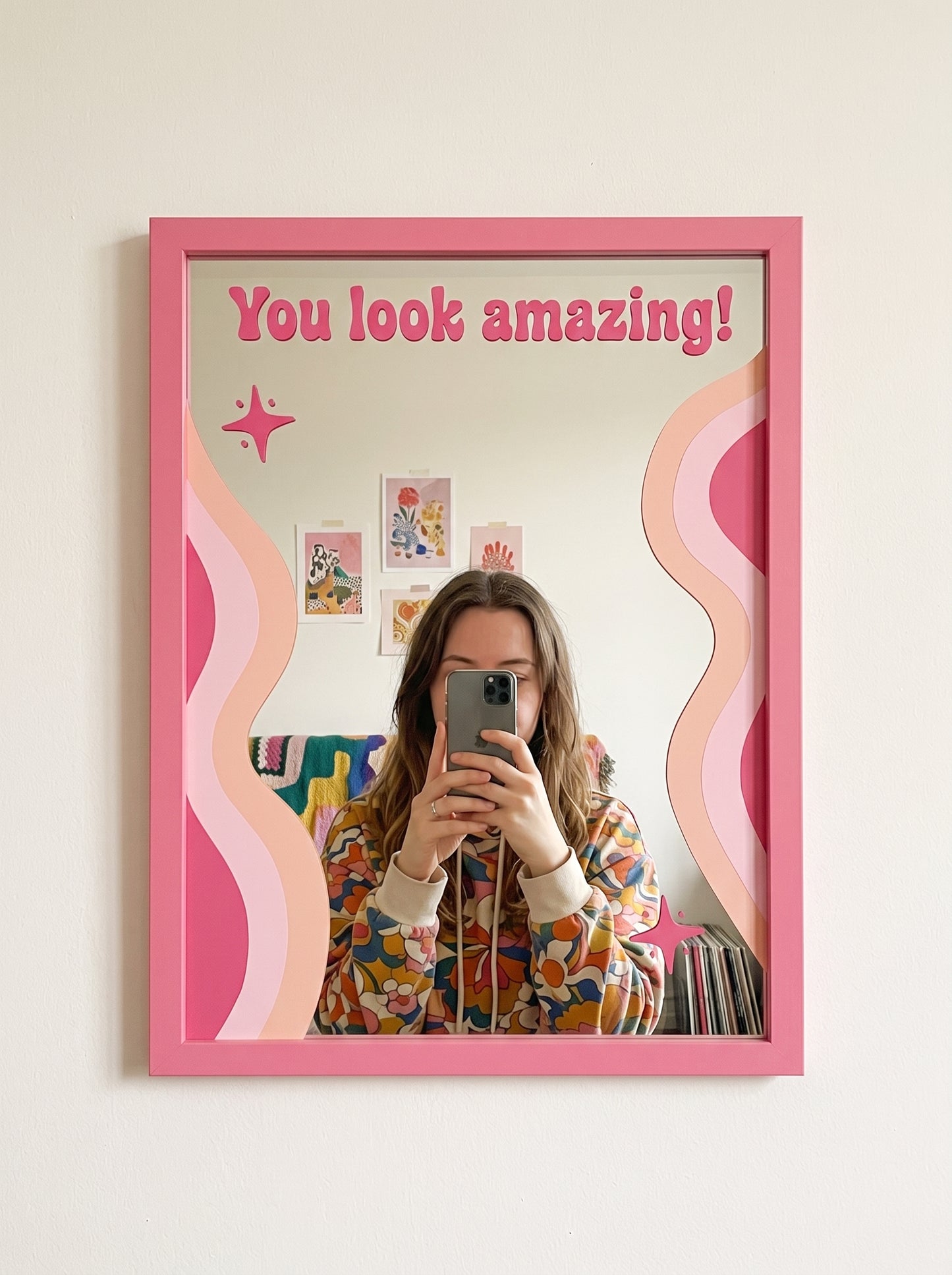 Pink wood-framed wall mirror with You look amazing! script text and wavy pink swirl accents